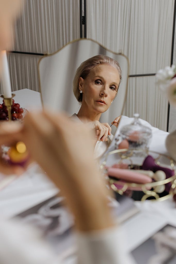 A mature woman looking at her reflection, showcasing elegance and beauty in a styled indoor setting.