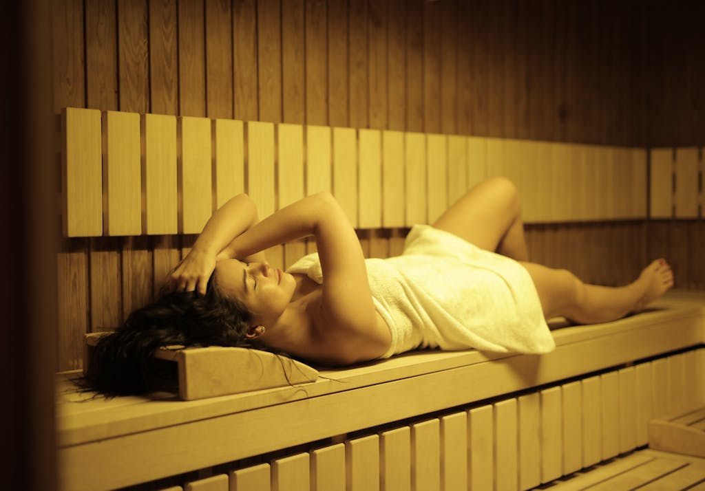A woman relaxing in a sauna wrapped in a towel, experiencing ultimate wellness and comfort.